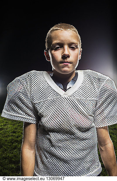 Porträt eines Jungen in American-Football-Uniform gegen den nächtlichen Himmel