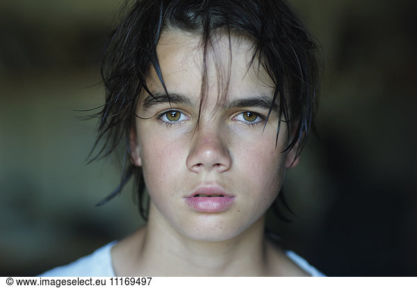 Porträt eines Jungen mit braunen Haaren und Augen  der in die Kamera schaut.