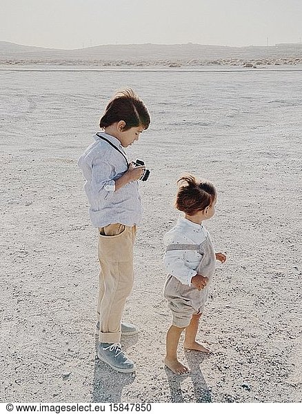 Porträt eines Kindes  das eine Kamera hält  während ein anderes Kind neben ihm steht