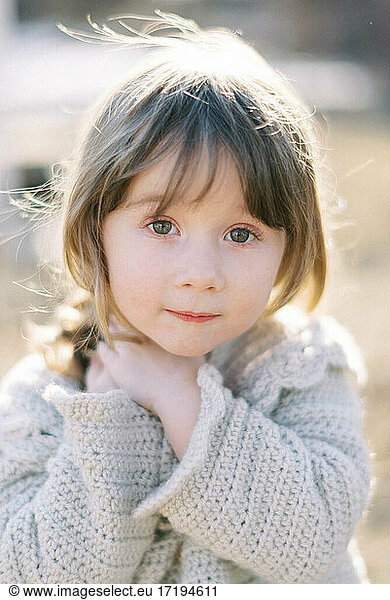 Porträt eines kleinen Mädchens bei Sonnenuntergang in einer gehäkelten Strickjacke