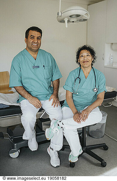 Porträt eines lächelnden Arztes und einer lächelnden Ärztin  die im Krankenhaus sitzen