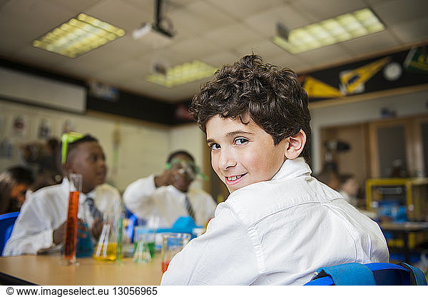 Porträt eines lächelnden Jungen  der im Labor am Tisch sitzt