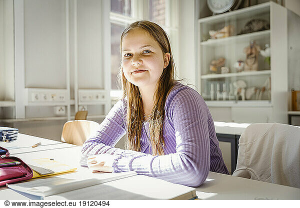 Porträt eines lächelnden Mädchens  das am Schreibtisch im Klassenzimmer sitzt