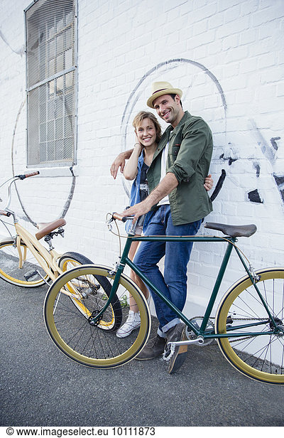 Porträt eines lächelnden Paares mit Fahrrädern an der Stadtmauer