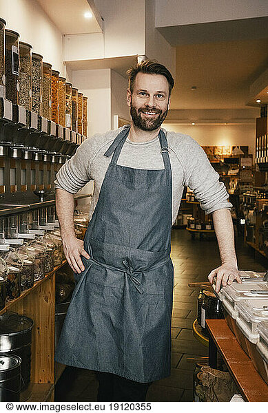 Porträt eines lächelnden reifen Besitzers  der in einem Geschäft arbeitet
