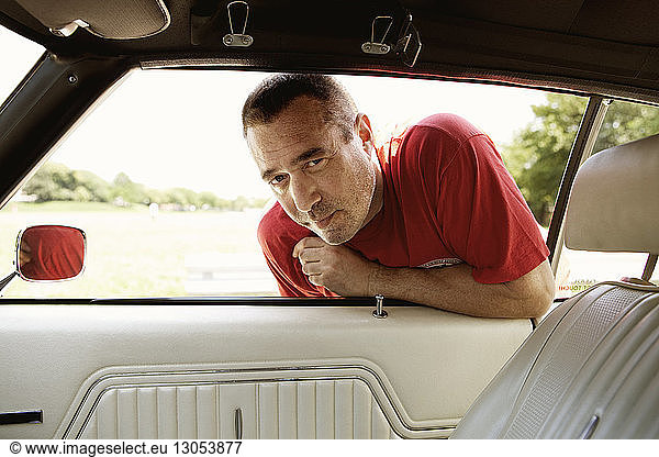 Porträt eines Mannes  der sich an ein Autofenster lehnt