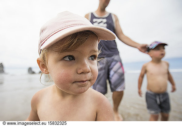 Porträt eines süßen einjährigen Mädchens am Strand mit Bruder und Papa.