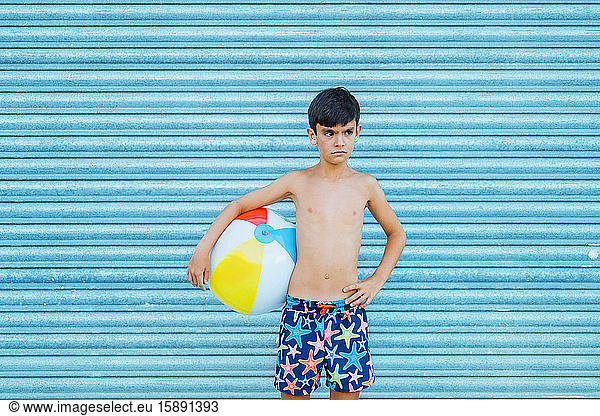 Porträt eines schlecht gelaunten Jungen  der einen Strandball hält