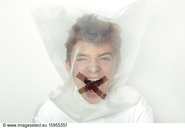 Porträt eines schreienden Teenagers mit durchsichtiger Maske mit Kreuz auf dem Mund