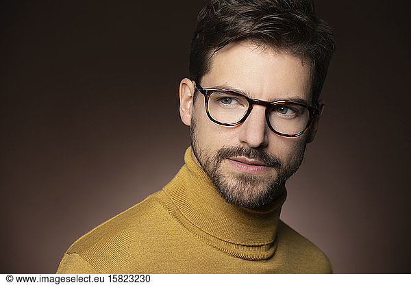 Porträt eines selbstbewussten Mannes mit Brille und gelbem Pullover