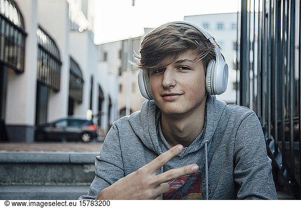 Porträt eines Teenagers mit Kopfhörer mit Siegeszeichen
