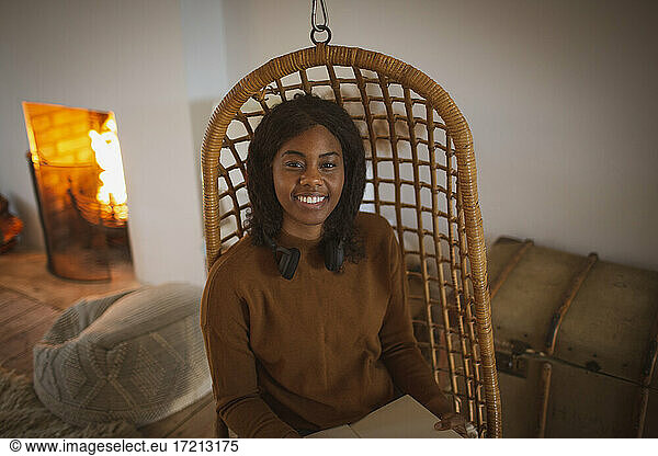 Porträt glückliche junge Frau lesen Buch in hängenden Rattan Stuhl