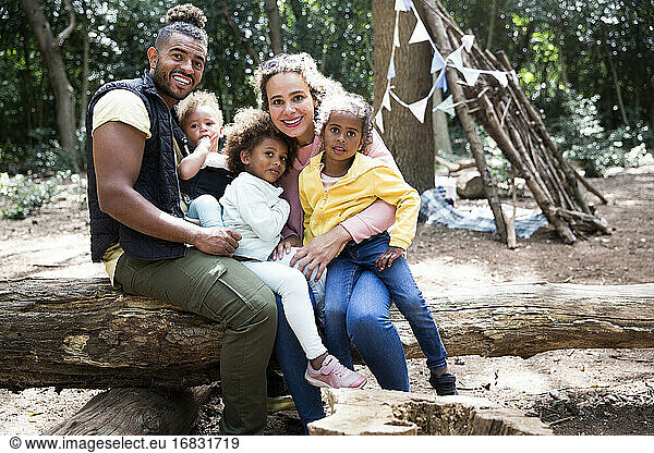 Porträt glückliche liebevolle Familie auf gefallenen Stamm im Wald