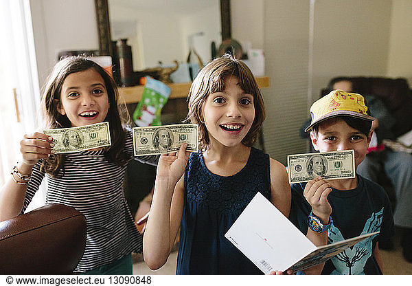 Porträt glücklicher Geschwister zeigt US-Papiergeld zu Hause