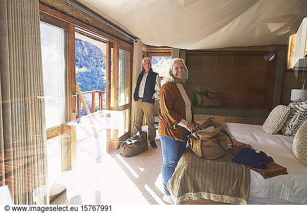 Porträt glückliches älteres Paar beim Auspacken im sonnigen Hotelzimmer