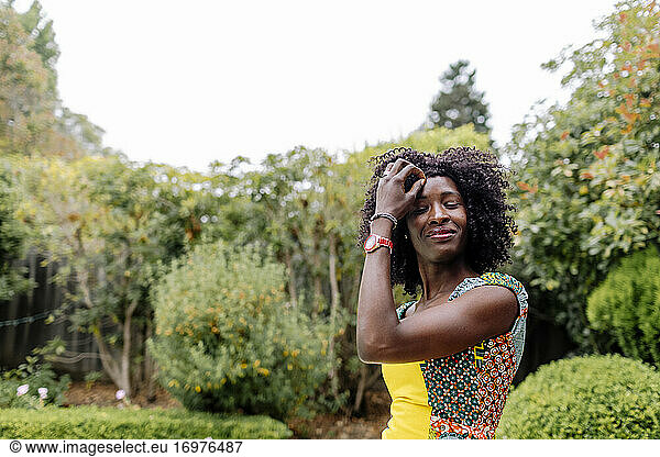 Porträt im Freien afrohaarige Frau mit Blick nach unten durch Grünpflanzen