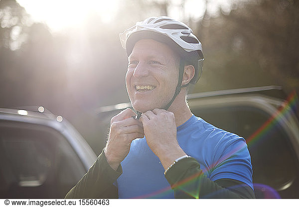 Porträt lächelnder Mann  der seinen Fahrradhelm befestigt