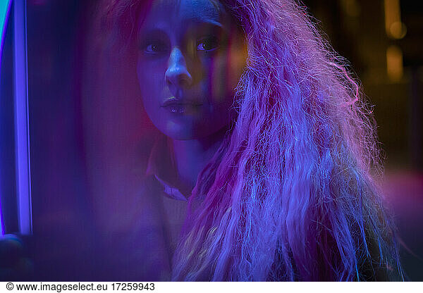 Porträt schöne geheimnisvolle Frau mit rosa Haaren in Neonlicht