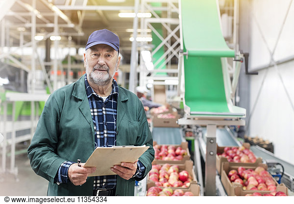 Porträt selbstbewusster Manager mit Zwischenablage in der Apfelverarbeitungsanlage