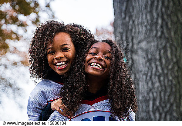 Porträt von fröhlichen Schwestern in Sportkleidung im Park