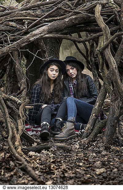 Porträt von Freundinnen  die inmitten von Wurzeln im Wald von Epping sitzen