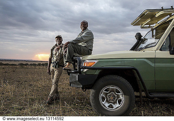 Porträt von männlichen Freunden im Geländewagen im Serengeti-Nationalpark bei Sonnenuntergang