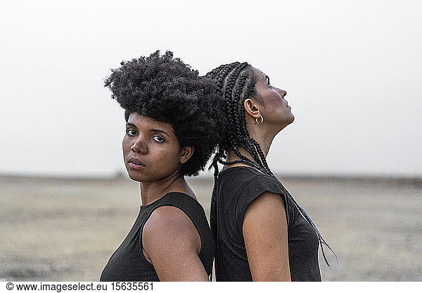 Porträt von zwei Frauen Rücken an Rücken in trostloser Landschaft