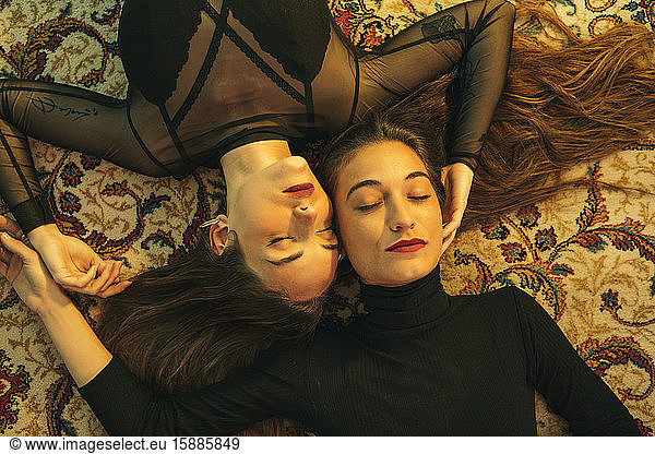 Porträt von zwei jungen Frauen  die Kopf an Kopf auf dem Boden liegen