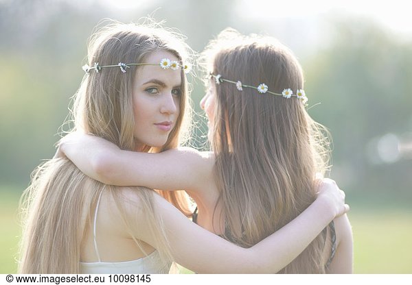 Porträt von zwei Teenagermädchen in Gänseblümchen-Kopfbedeckung im Park