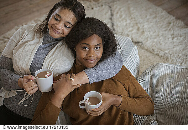Portrait affectionate mother and daughter cuddling with hot cocoa
