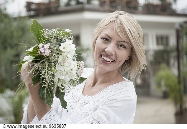 Portrait blond woman celebrating holding bouquet