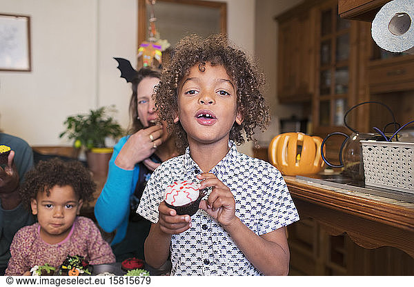 Portrait boy eating Halloween cupcake