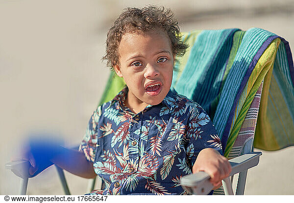 Portrait boy with Down Syndrome in beach chair