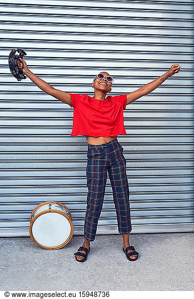 Portrait carefree young female musician with tambourine