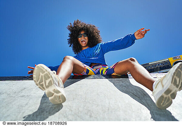 Portrait carefree young woman cheering at sunny sports ramp