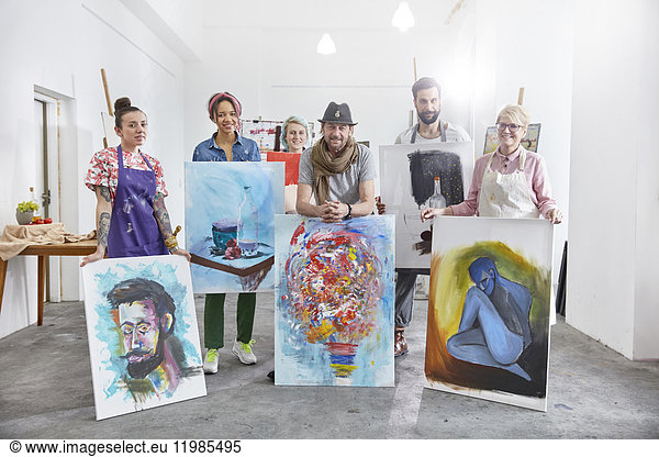 Portrait confident artists showing paintings in art class studio