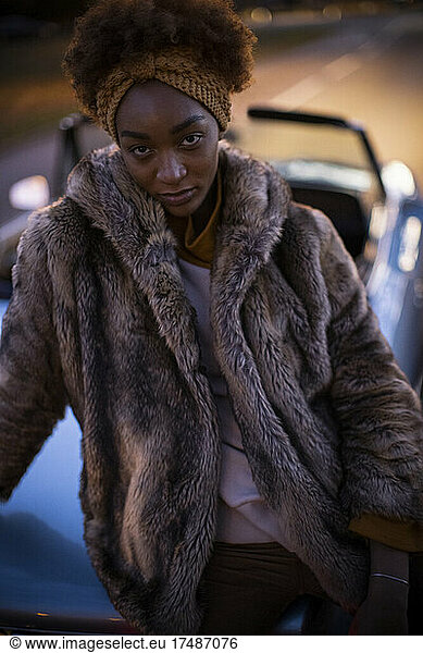 Portrait confident beautiful young woman in fur coat at convertible