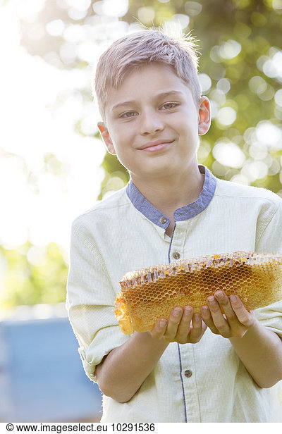 Portrait confident boy holding fresh honeycomb