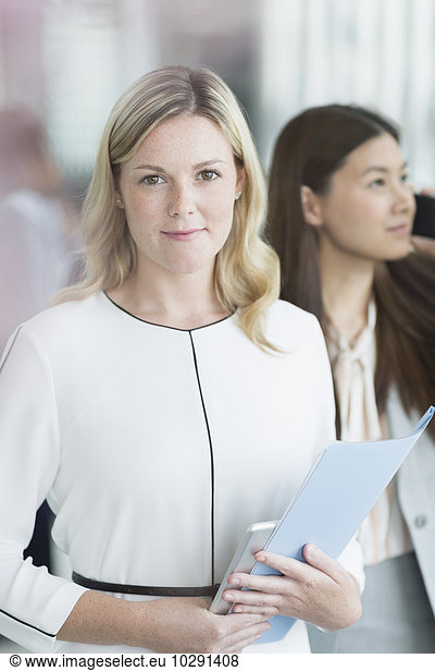 Portrait confident businesswoman with folder and digital tablet