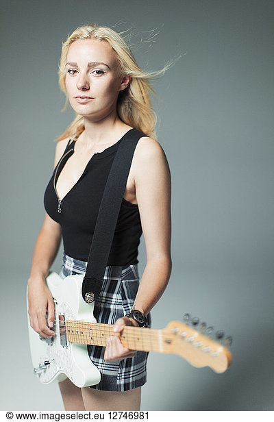 Portrait confident  cool young woman playing electric guitar