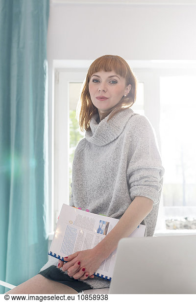 Portrait confident creative businesswoman holding notebook in office