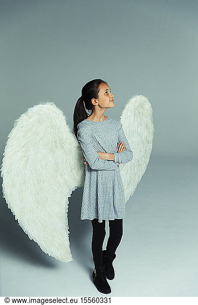 Portrait confident  curious girl wearing angel wings  looking up