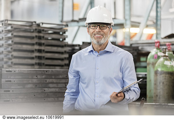 Portrait confident engineer with clipboard in factory