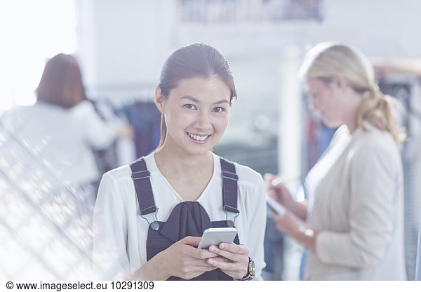 Portrait confident fashion designer texting with cell phone