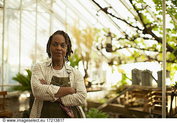 Portrait confident female garden shop owner in greenhouse