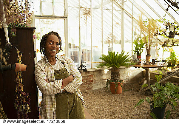 Portrait confident female garden shop owner in greenhouse
