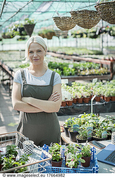 Portrait confident female garden shop owner working in greenhouse