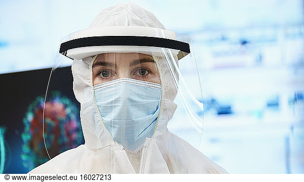 Portrait confident female scientist in clean suit studying coronavirus