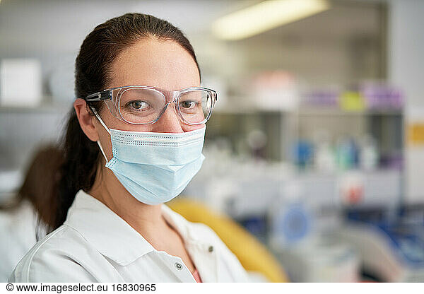 Portrait confident female scientist in face mask in laboratory