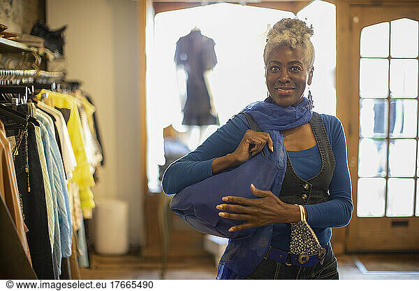 Portrait confident female shopper with blue handbag in shop